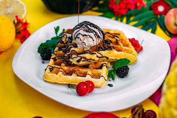 Traditional Belgian waffles with berries and ice cream on a decorated table