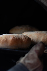 Hot homemade bread with moisture vapor freshly made in a Chilean clay oven with white flour and women's hands Cordoba Argentina