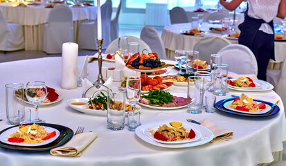 Decor and decoration of the festive table.Banquet table festive at the event in the restaurant. Wine glasses for wine. Plates with snacks. Fruit. A set festive table. The waitress.