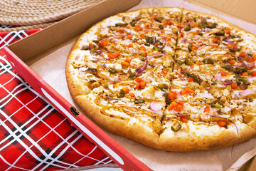 Pizza in a cardboard delivery box on a red checkered tablecloth. Fast food delivery service, Italian cuisine. A party. Copy space