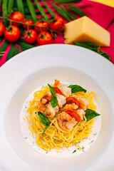 spaghetti with shrimps and tomatoes on a decorated table