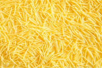 Dry pasta close-up. Culinary background, texture, pattern of yellow vermicelli. Copy space