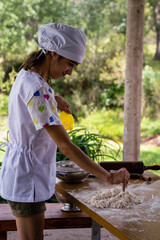 Obraz premium young woman dressed as a bakery making bread with flour eggs background green field with sun on vacations cordoba argentina