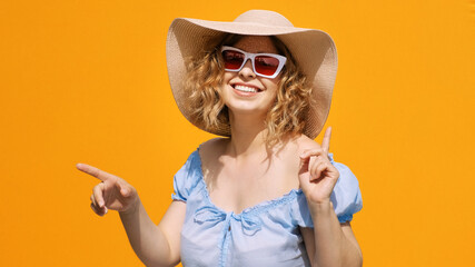 Portrait of happy woman in stylish sunglasses in hat smiling dancing to music rhythmically moving her hands and body on yellow background. Emotions of people. Positive girl. Freedom. Lifestyle