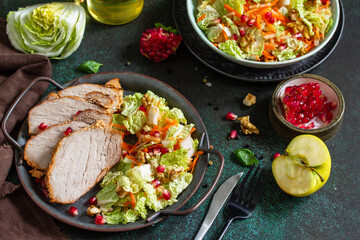 Healthly food. Baked meat steak salad and Chinese cabbage salad with apple, pomegranate, walnuts and on a stone tabletop.