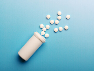 Open container with pills on  blue background.