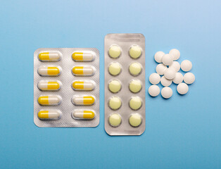 Colored Pills packed in blisters on blue background.