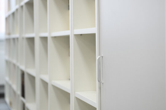 White cabinet with open shelves for storing books, library at school.