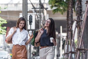 Fototapeta premium Young shopaholic friends women friends walking and carry shopping bags in the street city with happy and smiling.
