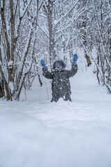 Smiling child playing with snow outdoors. Boy having fun in winter park with friends in vacation and holidays. Emotion, happiness, lifestyle concept.