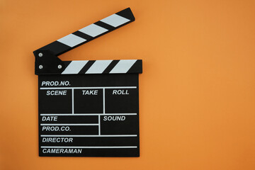 Fototapeta na wymiar Clapboard for the cinema production on the orange background