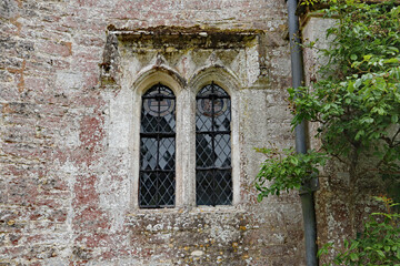 Fototapeta na wymiar An old arched leaded window with a concrete frame in an old English country house