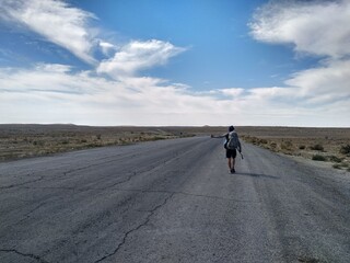 White man hitchhiking on an empty desert road in Turkmenistan