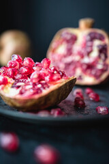 
Pomegranate and fresh pomegranate seeds on a plant and dark background