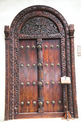 Die berühmten und historischen Haustüren im indischen Stil schmücken viele Häuser in Stone Town auf der Insel Sansibar. Die indischen Türen haben einen gewölbten Rahmen und Messingspitzen.