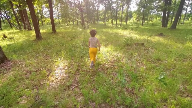 Slow motion. Teenage girl runs through wild oak forest