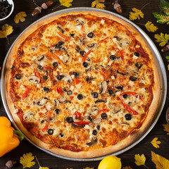 Just baked fresh Italian pizza with mozzarella and ham on the table with ingredients, cooked by a recipe from an online course. Homemade fast food meal for lunch.