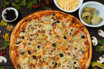 Just made fresh pizza with artichoke and olive, vegetarian meal with organic products. Fast food for lunch, ingredients on the background. Italian pizza recipe.