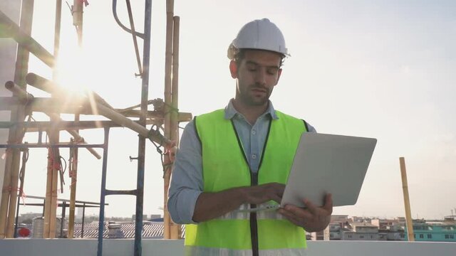 The engineer using a computer laptop and went to inspect the site's construction, and there was a steel scaffold in the back.