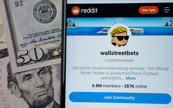 Wallstreetbets Reddit community web page seen on the smartphone screen and US dollars on a blurred background. Concept. Stafford, United Kingdom - January 30 2021.