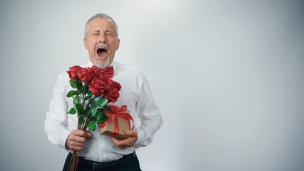 An elderly stylish grandfather with a bouquet of flowers in fashionable clothes