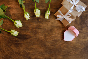 pink blank box for gold jewelry as a gift on a wooden background with white roses. The moment of a wedding, anniversary, engagement, or Valentine's Day. Happy day