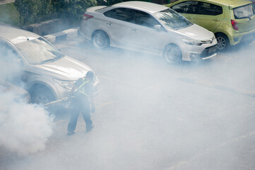 Healthcare worker using Fogging machine spraying chemical to eliminate mosquitoes and kill larvae to fight against the spread of dengue fever, Zika virus or Malaria at a residential area.