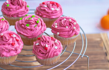muffins with scarlet cream and decor , pearls and red and green stars. holiday cupcakes on a metal stand on a wooden background. High quality photo