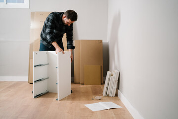 Portrait of man assembling furniture. Do it yourself furniture assembly. - 409505392