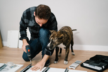 Portrait of man and his dog assembling furniture. Do it yourself furniture assembly.
