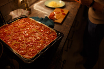 Tomatoes on a raw pizza. 