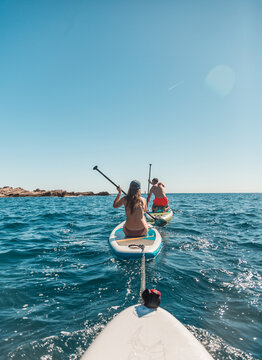 A group of people paddle with SUP stand up paddle boards on a hot day in the Adriatic sea in Montenegro