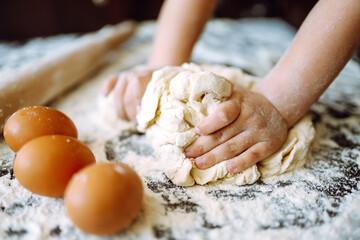 Children hands kneading dough on wooden table. Easter baking preparation. Cookies for Christmas. 