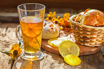 Chilled tea with lemon on a wooden table. Next on the kitchen breadboard with homemade cakes. Comfortably. House.Family.The concept of Good morning.