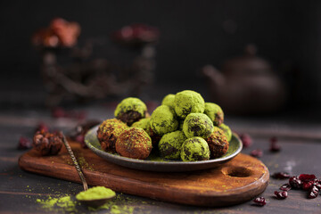 Matcha energy sweets balls made of dried fruits dusted with bright green matcha powder on rustic...