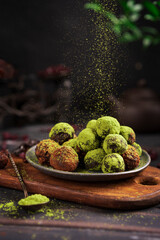 Matcha energy sweets balls made of dried fruits dusted with bright green matcha powder on rustic...