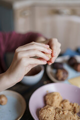 Obraz na płótnie Canvas Child hands making sweet balls cookies called Potato of marzipan, biscuits, cocoa. Process of dessert cooking, wooden table with ingredients. Selective focus, copy space