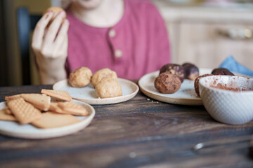 Child hands making sweet balls cookies called Potato of marzipan, biscuits, cocoa. Process of dessert cooking, wooden table with ingredients. Selective focus, copy space