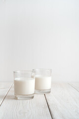 Two glasses of milk on a white background. Side view with copy space, vertical orientation. The concept of dairy products.