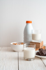 A glass of milk on a background of marshmallows, crackers and a bottle of milk on a white background. Side view, vertical orientation. The concept of dairy products.