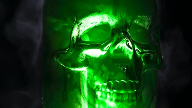 Glass Rotating Skull. Green glass skull slowly rotates on a black background in a couple of clubs