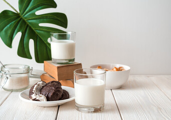 Fresh milk, marshmallows and crackers on a white background with a monstera leaf. Side view with copy space. The concept of food nutrition products.