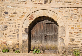 an ancient wooden door on a stone wall of an antique building