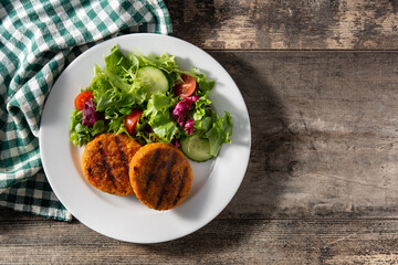 Delicious healthy chickpea burger and salad on wooden table. Top view. Copy space