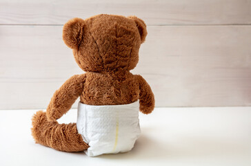 Baby teddy wearing diaper sitting on white color floor