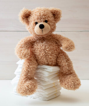 Baby diapers stack and teddy on white color floor