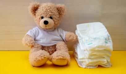 Baby diapers and teddy on yellow color floor