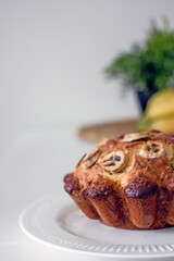 Homemade gluten free cake made from alternative flours, sugar free with banana and nuts on a white plate on a white table. Homemade baked goods and natural ingredients, healthy food, Home hobbies 