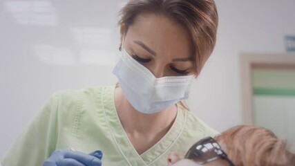 Beautiful female doctor working with patients older woman. Checks the condition of old teeth. Doctor examining teeth of old woman in chair. The girl puts medical instruments in her grandmother's mouth