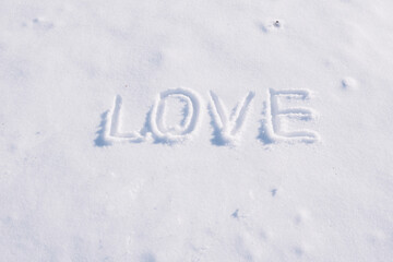 The word Love written on white snow